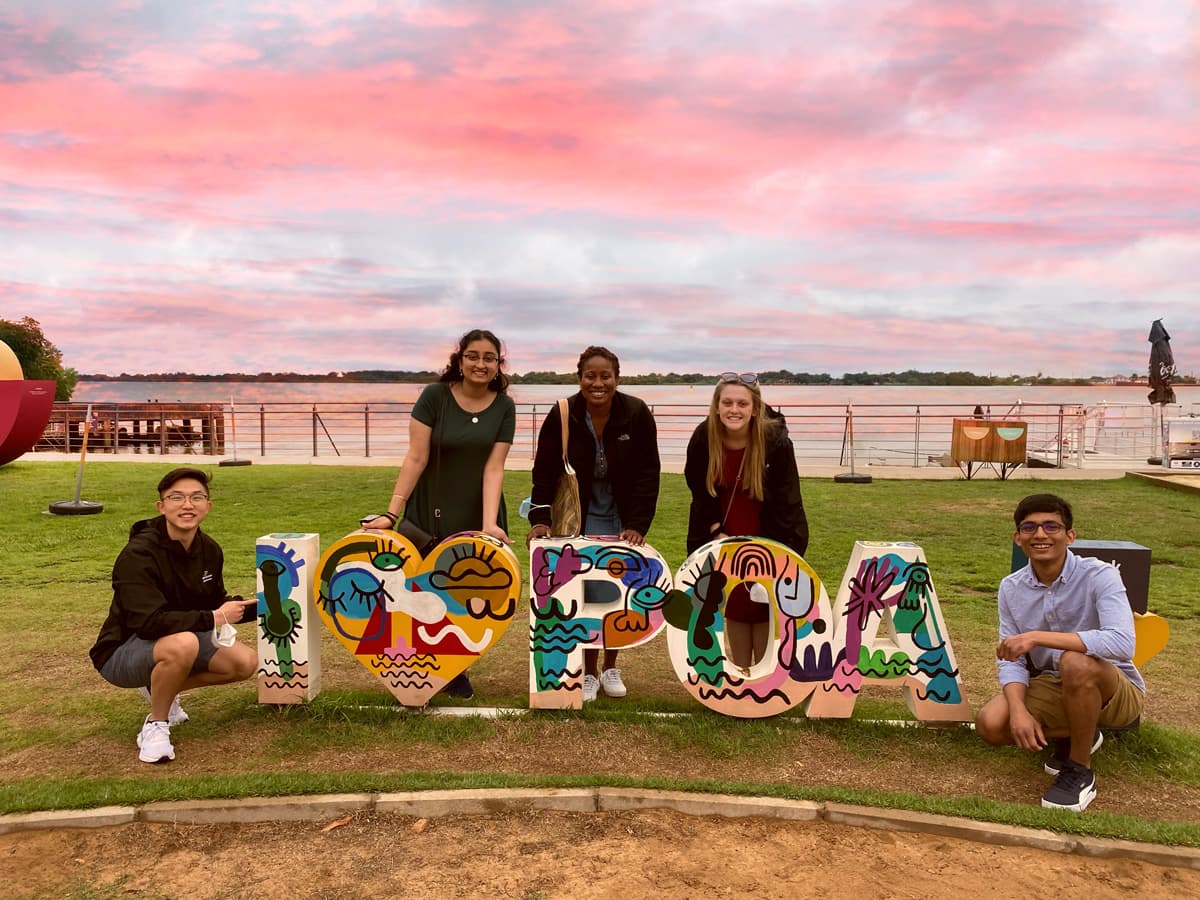 Five people pose behind colorful I LOVE POA letters.