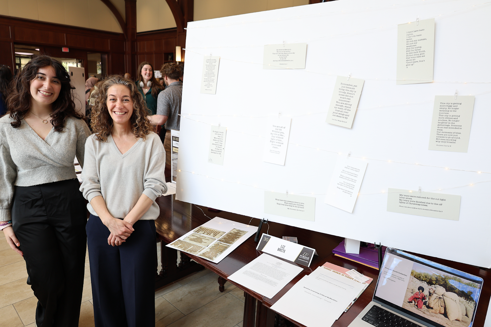 Liz Brite (right) stands next to her poster with poems her students collected as part of her course HONR 399: Beyond Afghanistan.